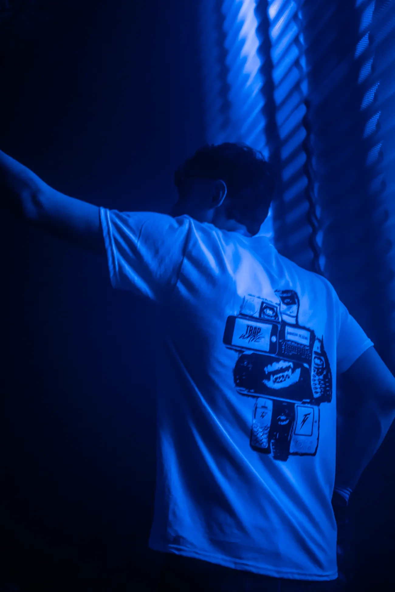 Someone wearing the white tee on the floor, back print lit blue.