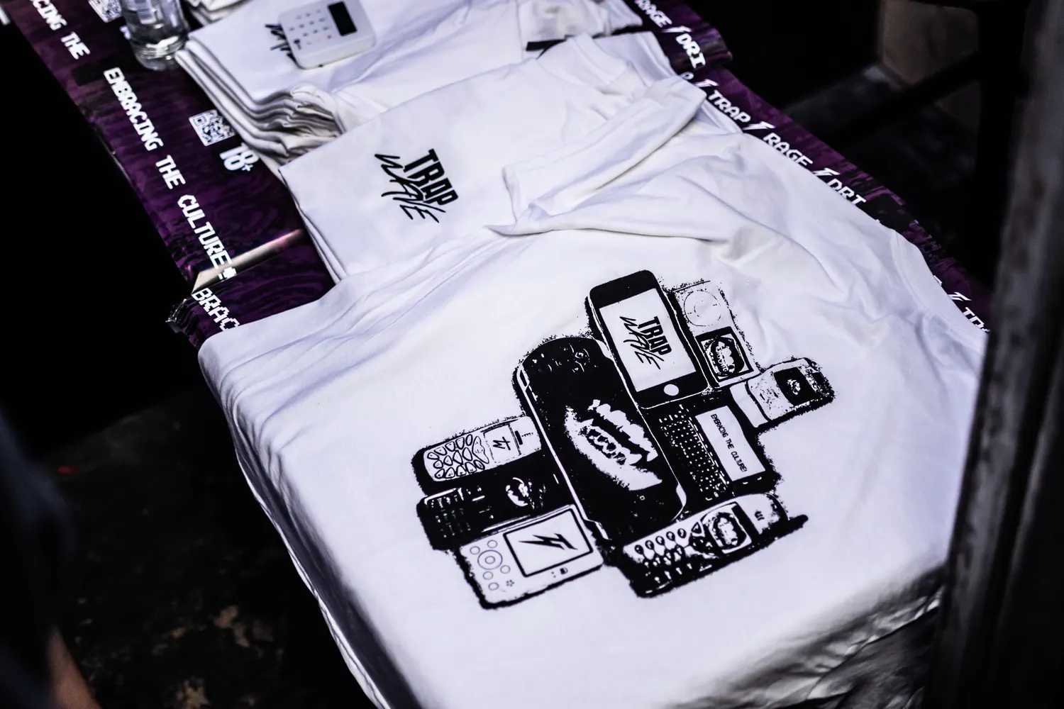 Folded tees stacked on the merch table beside a banner reading Embracing the culture.