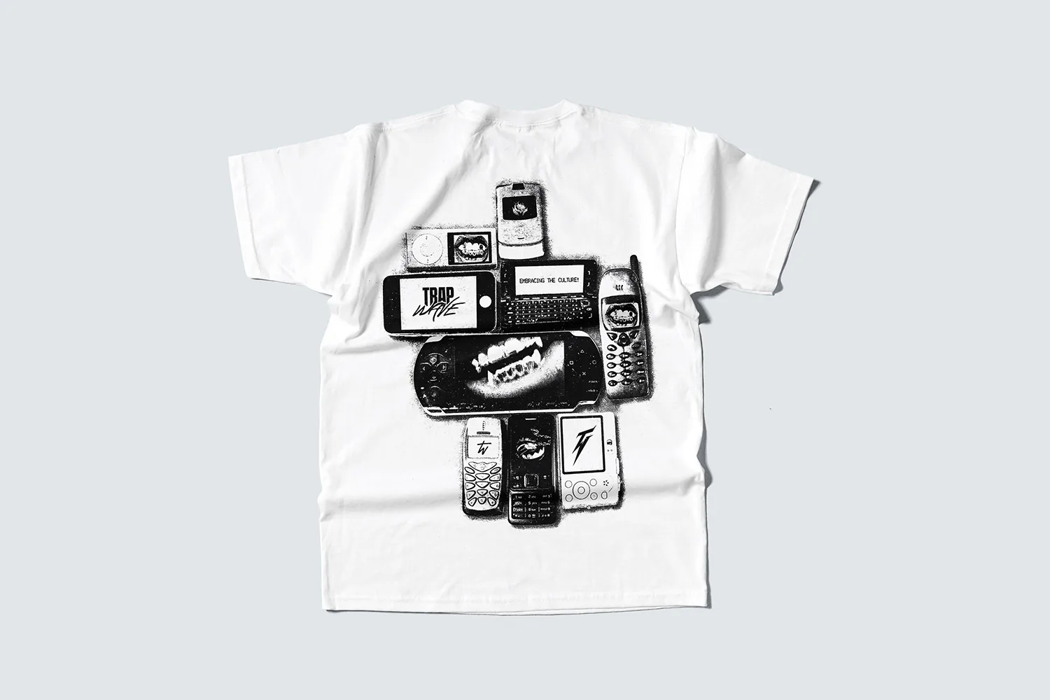 The back of the white tee: a black and white pile of old phones, a PSP and a handheld console.