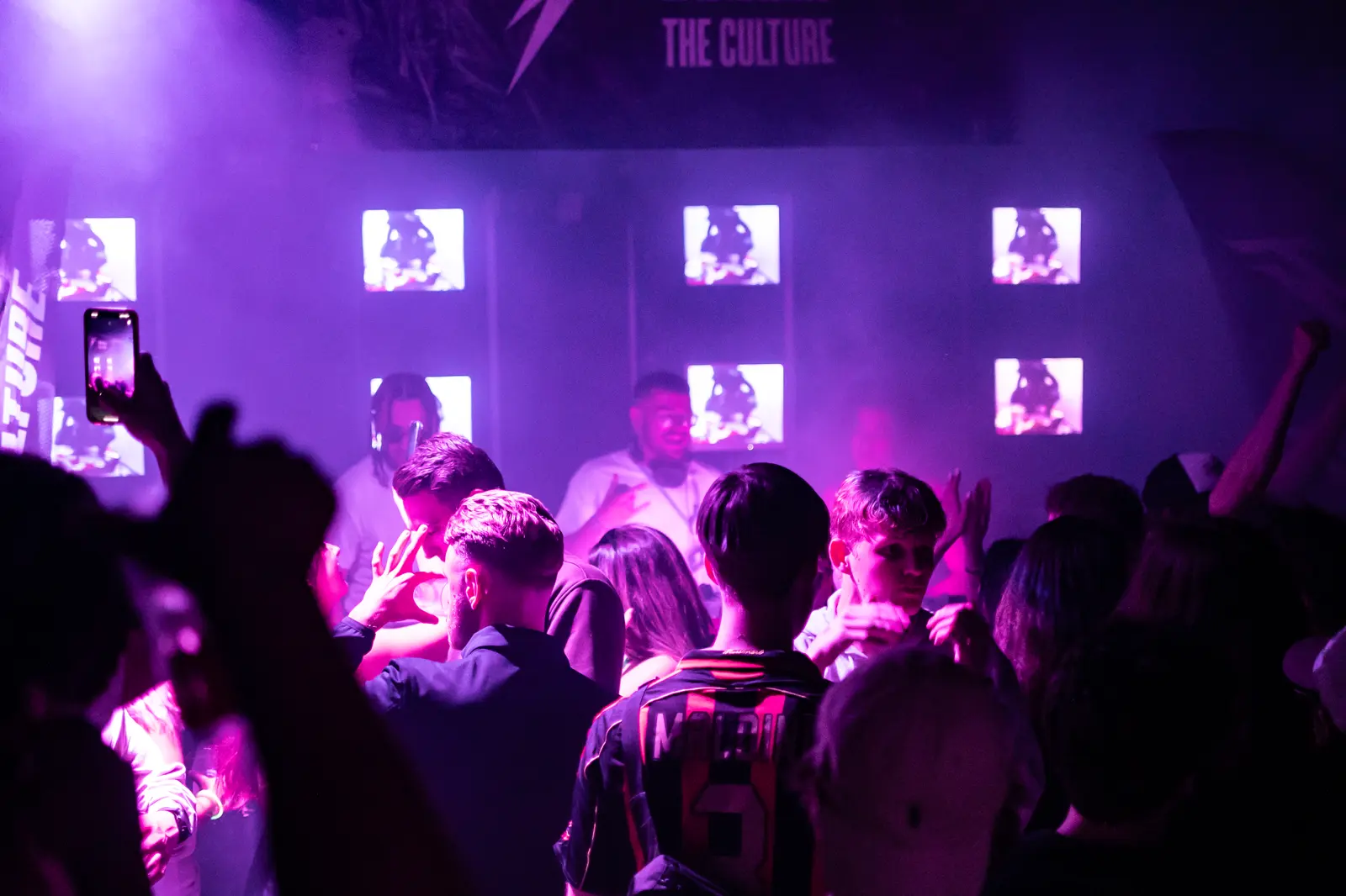The crowd facing a grid of six screens behind the booth.