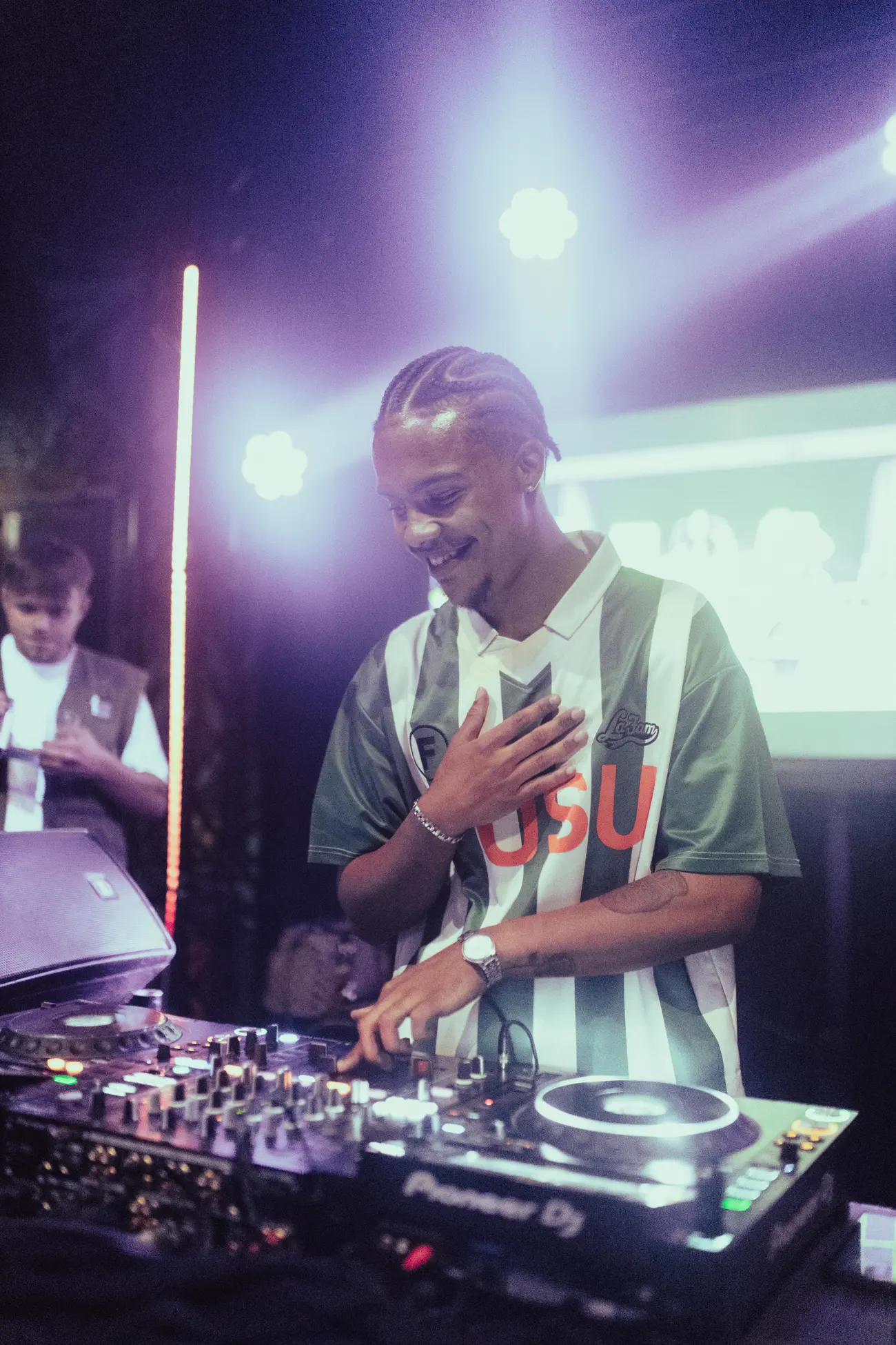A DJ laughing mid-set, hand on his chest.
